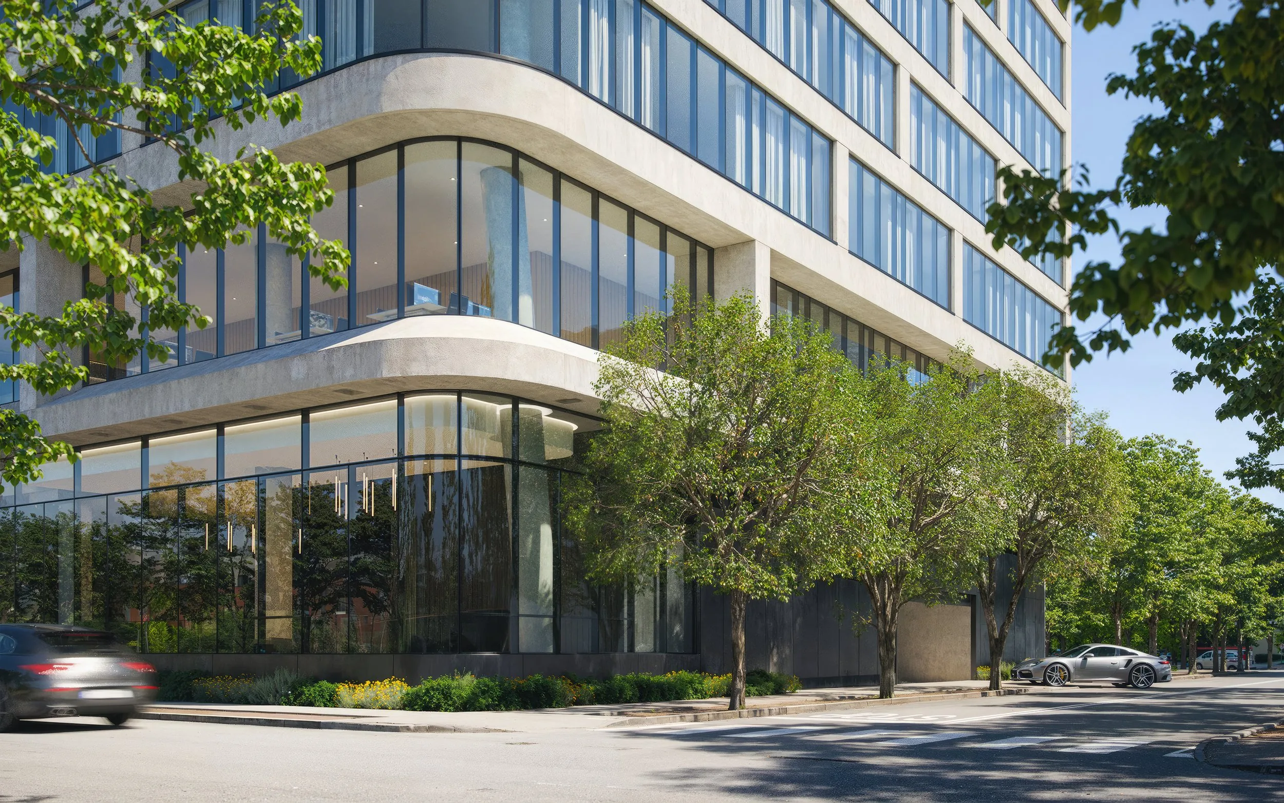 Street-level view of the curved corner and retail glazing among the trees