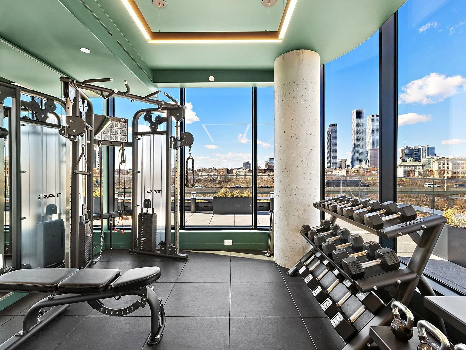 The gym as built on the amenity level, skyline beyond the equipment