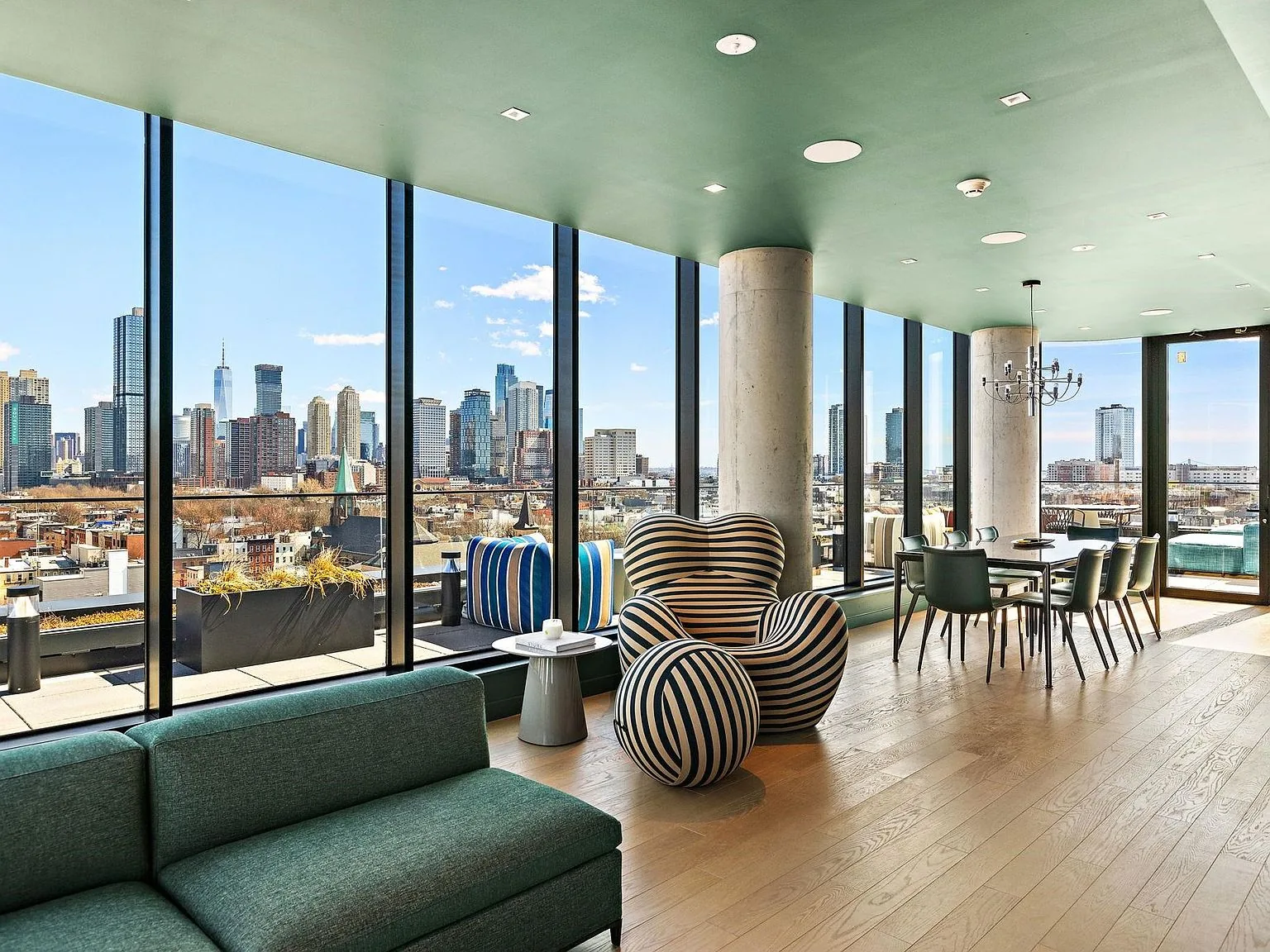 The rooftop residents' lounge as built, green seating against the Manhattan skyline